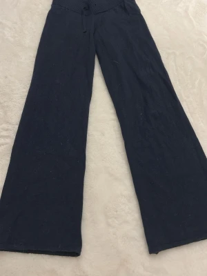 Mörkblå stickade byxor Gina Tricot - Mörkblå stickade byxor från Gina Tricot med bred resårmidja och snörning. Byxorna har en loose och wide passform med raka ben, perfekta för en avslappnad look. Materialet är mjukt och stretchigt för extra komfort. Sååå sköna.🥰