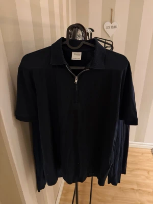 Mörkblå polo halvzip från Selected Homme - Säljer en mörkblå polo halvzip från Selected Homme med korta ärmar och klassisk krage. Toppen har en snygg half zip-dragkedja framtill och är gjord i mjuk bomull. Perfekt för en clean och stilren look. Storlek S passar även M, finns inga fläckar så väldigt fin