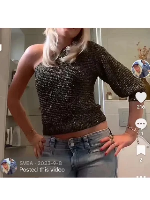 Glittrig one shoulder topp från MNG - Säljer en glittrig svart och guld one shoulder topp från MNG i storlek S. Toppen har en asymmetrisk design med en ärm och är croppad i modellen. Materialet är syntet med inslag av glittertrådar som ger en snygg effekt. Perfekt för att sticka ut med en cool look.