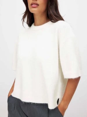 Vit stickad tröja med kort ärm - Säljer en vit stickad tröja med korta ärmar och rund hals. Tröjan har en loose passform och är tillverkad i mjukt material som känns skönt mot huden. Perfekt att styla med jeans eller kjol för en chill look.