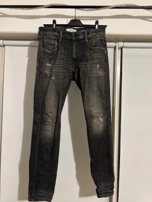 Replay Anbass svarta jeans - Säljer ett par Replay Anbass jeans i svart tvätt med slitna detaljer och snygg faded effekt. Jeansen har klassisk femficksdesign, smal passform och raka ben. Perfekta för dig som gillar en modern och avslappnad stil. De har inte blivit använda så mycket eftersom att formen inte passar mig jättebra, säljer dem eftersom att de är för små för mig. Köpte dem för 1800