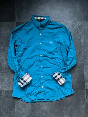 Burberry skjorta blå - Burberry skjorta blå i bra skick, använd en del. Endast skjortan ingår.