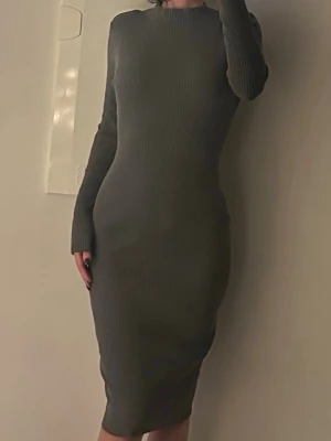 Grå ribbad långärmad klänning - Säljer en grå, ribbad långklänning med lång ärm och rund hals. Klänningen är figurnära och har en stilren, enkel design. Inköp H&M storlek S passar även XS