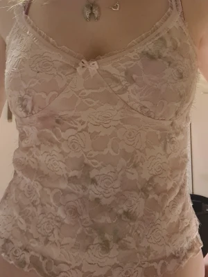 Rosa spetslinne - Söt ljusrosa linnetopp i genomskinlig spets men har ett vit/ljusrosa linne under som gör så det inte blir för genomskinlig. Linnet har en liten roset i mitten och smala axelband. Skriv om ni har frågor! 