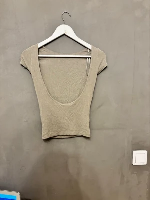 Grön topp med öppen rygg - Säljer en grön topp med korta ärmar och rundad halsringning med öppen rygg.