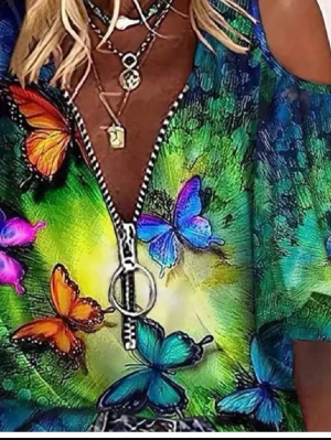 Färgglad topp med fjärilsmönster och dragkedja - Säljer en unik topp med färgglatt fjärilsmönster i blått, grönt, orange och rosa. Toppen har en stor rund dragkedja framtill och öppna axlar. Materialet är troligtvis polyester och toppen har korta ärmar. Perfekt för dig som gillar att sticka ut med färg och detaljer.