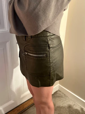 Brun, fejk läder och kort kjol med dragkedjor - Cool kortkjol från mango i storlek M - kjolen är i skinnimitation med dragkedjor på fickorna🫠🤎alldrig använt på grund av att den inte passade : midjemått 42cm😁