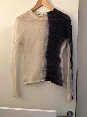 Svartvit stickad topp från Weekday - Säljer en långärmad stickad topp från Weekday i storlek XS. Toppen har en cool tvåfärgad design med ena sidan svart och andra sidan vit, och är gjord i ett tunt stickat material. Perfekt för dig som gillar unika plagg med lite edge.