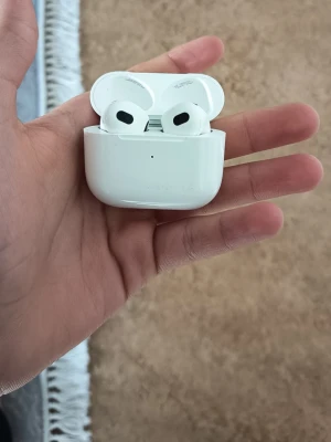 Apple AirPods 3 - Apple AirPods 3 i bra skick med laddningsetui. Trådlösa hörlurar med hög ljudkvalitet och bekväm passform. Laddningsfodralet har mindre ytliga repor men fungerar utmärkt. Perfekt för musik, samtal och träning.