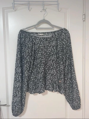 Svart blus från med vita småblommor - Svart blus från med vita småblommor över hela tyget och små knappar framtill 