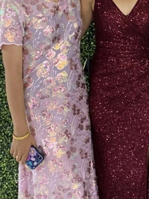 Ljuslila blommig långklänning - Superfin långklänning i ljuslila med blommigt mönster i pastellfärger. Klänningen har korta ärmar och är täckt av broderade blommor som ger en romantisk och elegant vibe. Perfekt för dig som vill sticka ut med en unik och färgglad look.