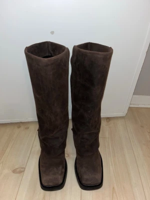 Mocka boots  - Säljer ett par höga boots i mörkbrunt mocka. Sparsamt använda, dock har de gått sönder lite inuti se bild. Inget som syns utåt eller stör när man har på sig dem. Går lätt att sy igen. 