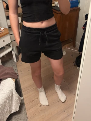 Svarta shorts från H&M Divided - Svarta mjuka shorts från H&M Divided med elastisk midja och snörning framtill. 