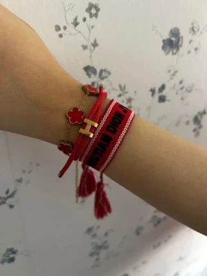 3st armband i röd färg  - Säljer en röd väst från Christian Dior med broderad svart text och vita detaljer. Västen har en klassisk rak form och är tillverkad i ett syntetmaterial. Passar dig som gillar statement-plagg och vill sticka ut med en ikonisk design.