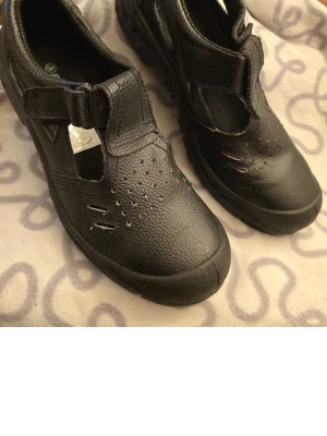 Skyddssandaler - Säljer ett par svarta skyddssandaler  slitstarkt med kardborrestängning. Skorna har perforerade detaljer för ventilation och förstärkt tå. Perfekta för dig som vill ha bekväma och tåliga arbetsskor med öppen design