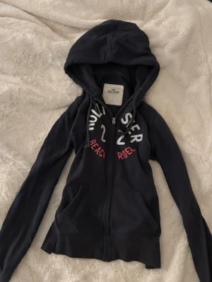 hollister vintage kofta yk2 - mörkblå huvtröja/zip kofta från hollister med rosa tryck. fint skick, stl L men absolut mer som en S💕