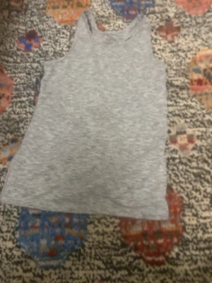 Grått ribbat linne - Säljer ett enkelt och stilrent grått linne i ribbat material. Linnet har rund halsringning och ärmlös design, perfekt att matcha med jeans eller kjol. Passar dig som gillar en clean och avslappnad look.