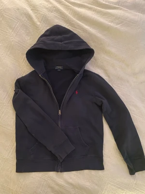 Polo Ralph Lauren hoodie - Mörkblå hoodie med dragkedja från Polo Ralph Lauren. Storleken är L 14-16 år men passar som 10-12 år. Passar från 130-150cm. Perfekt present till lillsyskonet eller barnet🤩