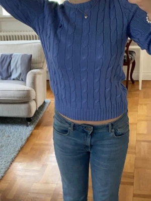 Ljusblå stickad tröja Polo Ralph Lauren - Säljer en ljusblå kabelstickad tröja från Polo Ralph Lauren i storlek M. Tröjan är gjord av mjuk pima bomull, har lång ärm och rund hals. Har nog använt den typ en gång för två år sedan, annars är den inte använd. Nypris ca 2000kr.
