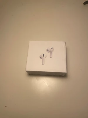 Apple AirPods Pro med laddningsetui - Säljer ett par Apple AirPods Pro med vitt laddningsetui och extra silikonpluggar i olika storlekar. Hörlurarna är trådlösa in-ear-modell i klassisk vit färg och har en stilren, minimalistisk design. Perfekta för musik, samtal och träning.