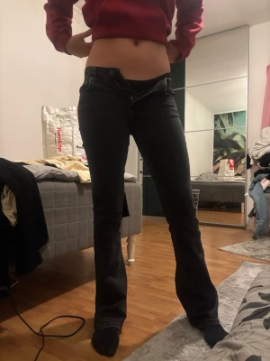 Mörkblå bootcut jeans - Snygga mörkblå bootcut jeans med låg midja och klassisk femficksdesign. Jeansen har en lätt utsvängd passform nertill och stängs med knapp och dragkedja. Perfekta för en trendig och avslappnad look.