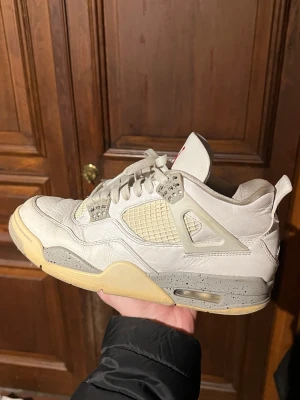 Nike Air Jordan 4 Retro Oreo - Snygga Air Jordan 4 Retro Oreo sneakers i beige och vitt läder med meshpaneler och grå detaljer. Sulan är beige med grått stänkmönster och den klassiska röda Jumpman-loggan syns på plösen. Perfekta för dig som gillar streetwear och unik design. Kom gärna med frågor eller vid behov av fler bilder! Har stock X kvitto!