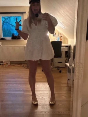 Vit kort klänning med puffärm - Supersöt vit klänning med broderade blommor och puffiga ärmar. Klänningen har v-ringning och en luftig, kort passform som ger en trendig look. Perfekt för dig som ska ta studenten till sommaren! 