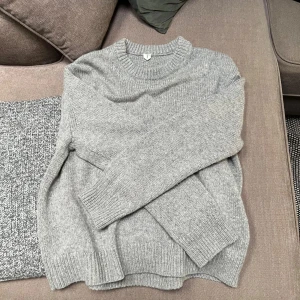 Grå stickad tröja från arket  - Säljer en stilren och bekväm grå stickad tröja från arket Perfekt för kyliga dagar med sin mjuka och varma känsla. Säljer den pga av att den är lite förstor för mig. Har aldrig användt den!