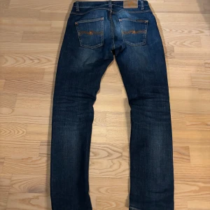  Nudie Jeans grim Tim - Säljer ett par blå Nudie jeans i Modellen Grim Tim.  Har haft dem i några år så de har fått ett feta fades. Storlek 29/30! 