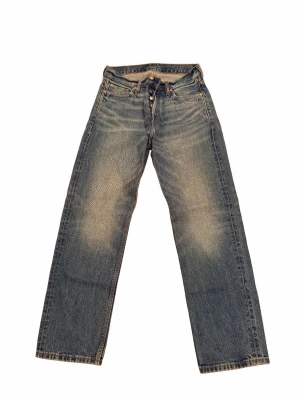 Blå raka jeans med knäppning - Klassiska blå jeans med raka ben och knappgylf. Jeansen har en snygg tvätt med slitningar på låren och femficksdesign. Perfekta för en avslappnad och trendig stil. Perfekt passform och sitter bra vid höft och längst benen. 