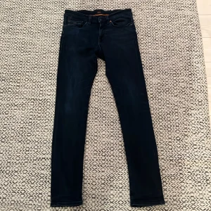 Mörkblå skinny jeans från Boss - Snygga mörkblå slimmed jeans från Boss med klassisk femficksdesign och diskreta kontrastsömmar. Jeansen har en smal passform och är perfekta för en stilren look. Materialet är stretchigt för extra komfort. Saknar helt och hållet skador! Kom med alla prisförslag kan sänka!