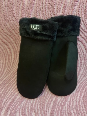 Svarta tumvantar från UGC Fashion - Mysiga svarta tumvantar från UGC Fashion med mjuk fuskpäls vid mudden. Vantarna har en stilren design och är perfekta för kalla dagar. Materialet känns mjukt och varmt, och pälsdetaljen ger en extra touch av stil.