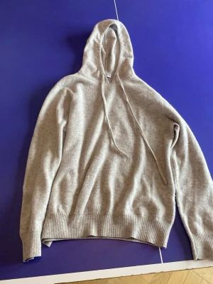 Grå hoodie med armbågslappar - Säljer en stilren bärs kachmir hoodie med huva och dragsnören. Tröjan har ribbade muddar vid ärmslut och nederkant samt mörkgrå armbågslappar på båda ärmarna. Nästan helt oanvänd så inte defäkter alls, otrligt bra pass form och riktigt skön tröja, Skicka gjärna pris försloag och om du vill ha mer bilder