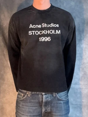 Svart långärmad topp Acne Studios (helt ny) - Cool svart långärmad topp från Acne Studios med vit text 'STOCKHOLM 1996' framtill. Klassisk rund halsringning och rak passform. Perfekt till jeans för en clean och stilren look. Fraktar samma dag. Allt og ingår. Pris kan diskuteras ;)