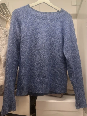Blå stickad tröja  - Mysig blå stickad tröja med rund halsringning och långa ärmar. Tröjan har en enkel, avslappnad passform och ribbstickade muddar vid ärmslut och nederkant. Perfekt för lager på lager under kyliga dagar.