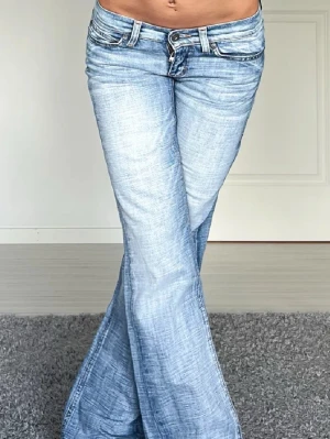 Ljusblå bootcut jeans från Only - Snygga ljusblå bootcut jeans från Only med låg midja och slitna detaljer. Jeansen har klassiska fem fickor, dragkedja och knapp framtill samt tydliga sömmar och logga på bakfickan. Perfekta för en trendig och avslappnad look. W34 L34. Midjemåttet är 38 cm rakt över och innerbenslängden är 84 cm. 