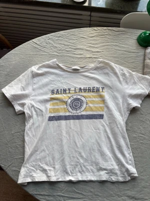 Saint Laurent t-shirt - Säljer denna Saint Laurent T-shirt, lite skön vintage känsla på den. Har lite mer av en croppad fit. Passar dig som har storlek small i vanliga fall. Hör av dig för fler frågor mvh Charlie