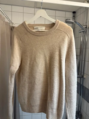 Beige stickad tröja A Days March - Mysig beige stickad tröja från A Days March med rund halsringning och ribbade muddar vid ärmslut och nederkant. Tröjan har en enkel och stilren design, perfekt för lager på lager och passar till det mesta. 