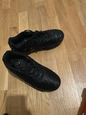 Nike Air helsvarta sneakers - Svarta Nike Air sneakers med klassisk siluett och låga snörade skaft. Ovandelen är i syntetmaterial med diskreta detaljer och Nike-logga på plösen. Snygg och tidlös modell som funkar till det mesta. Sulan är robust och ger bra komfort.