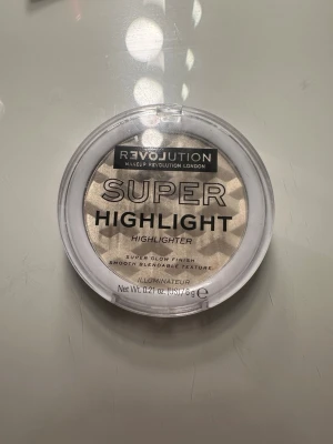 Revolution Super Highlight highlighter - Endast provad 😊Säljer en Revolution Super Highlight highlighter i en rund plastförpackning. Pudret har en skimrande champagnefärg och ett geometriskt mönster i ytan. Ger superglow och har en mjuk, lättblendad textur som passar perfekt för att framhäva ansiktets drag.