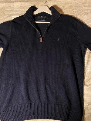 Mörkblå stickad tröja Polo Ralph Lauren - Tröjan passar S och M. Mörkblå stickad tröja från Polo Ralph Lauren med halv dragkedja och ribbad krage. Tröjan har broderad logga på bröstet och är tillverkad i bomull. Perfekt för lager-på-lager och snygg till jeans. PRIS KAN DISKUTERAS