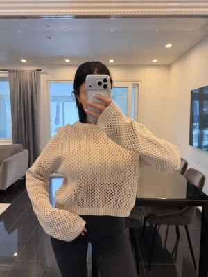 Beige stickad tröja med vida ärmar - Trendig beige stickad tröja med grovstickat mönster och vida, långa ärmar. Tröjan har en rak, något kortare passform och ribbade muddar vid ärmslut och nederkant. Perfekt för lager-på-lager och chill vibes.