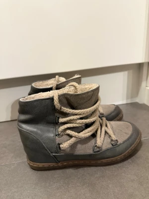 Grå höga sneakers med foder - Söta skor med fordring! Ovandelen är i en kombination av mocka och läderimitation, det är en liten kilklack i. Storlek 37. En metall ögla har försvunnit och ena har jag lagat därför säljs de billigt (sista bilden). 