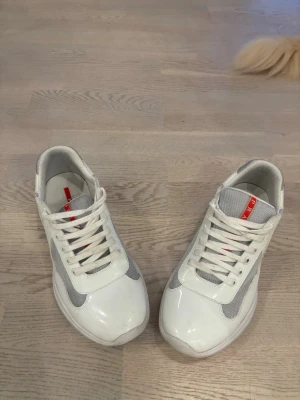 Vita sneakers från  med meshdetaljer - Snygga vita sneakers från  med grå meshdetaljer och klassisk röd logga på plösen. Skorna har snörning och en chunky sula som ger en modern look. Perfekta för dig som vill ha både stil och komfort i vardagen.