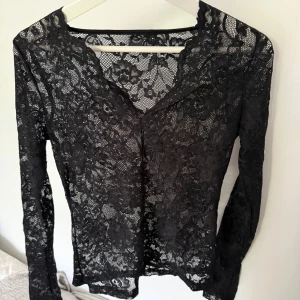 Svart spetsblus med v-ringning - Svart blus i spets med v-ringad hals och lång ärm!