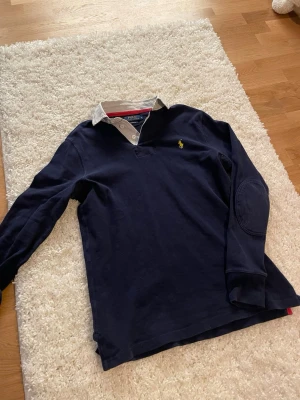 Ralph Lauren Långärmad Piké  - Tja. Säljer en väldigt trendig långärmad piké från märket Ralph Lauren. Sparsamt använd, skicket är perfekt. Tröjan är strl S men skulle säga att den passar S/M. Hör av dig om du har några funderingar. 