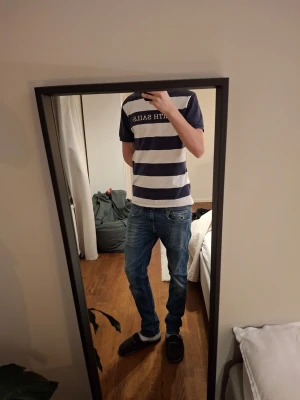 Replay Grovers blå jeans herr - Säljer ett par blå Replay Anbass jeans med klassisk femficksdesign och snygga slitningar. Jeansen har normal passform och raka ben, tillverkade i mjuk bomullsdenim med lite stretch för extra komfort. Perfekta för en avslappnad och trendig look.