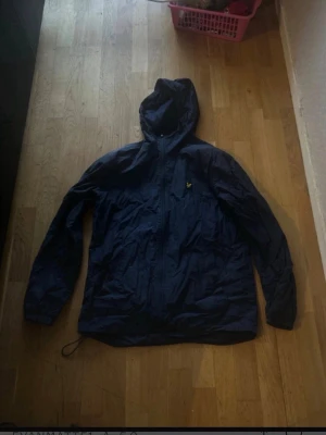 Marinblå vindjacka från Lyle & Scott M - Säljer denna fina jackan som inte kommer till användning har varit i garderoben länge så ingen behov av att ha den obs jag kommer inte sänka då den är redan billig obs jag vet inte mätt och bredd de ända jag vet att den är storlek M 