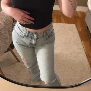 Ljusblå raka jeans från Zara  - Säljer ett par ljusblå raka jeans från Zara med klassisk femficksdesign och knappgylf. Jeansen har en hög midja och är tillverkade i denim med en snygg tvättad look. Perfekta för dig som gillar en avslappnad och tidlös stil.