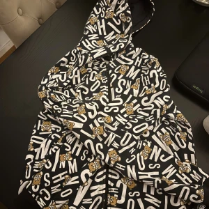 Svart och vit Moschino tröja med  björnar - Säljer en svart zip-hoodie från moschino i bra skick och väldig skön att ha på sig , storlek m , säljs för 700 , finns inte många sånna koftor !!